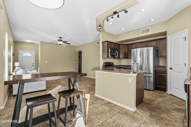 kitchen with dark stone countertops, dark brown cabinets, ceiling fan, and appliances with stainless steel finishes