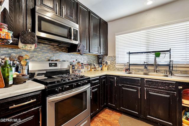 kitchen featuring sink, appliances with stainless steel finishes, backsplash, dark brown cabinetry, and light wood-type flooring