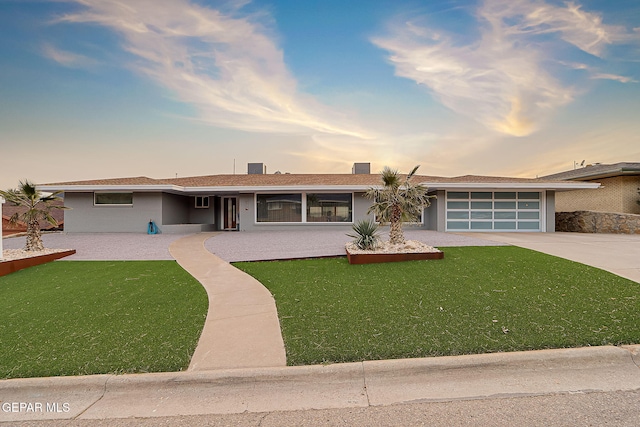 single story home featuring a garage and a yard