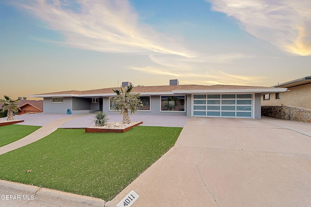 ranch-style home with a garage and a lawn