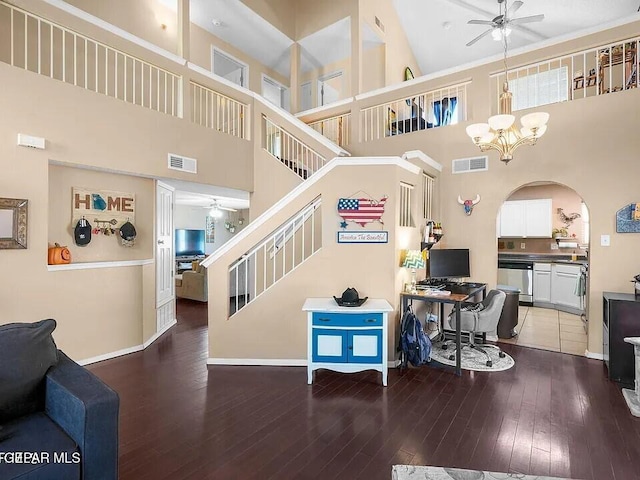 staircase featuring ceiling fan with notable chandelier, a towering ceiling, and hardwood / wood-style floors