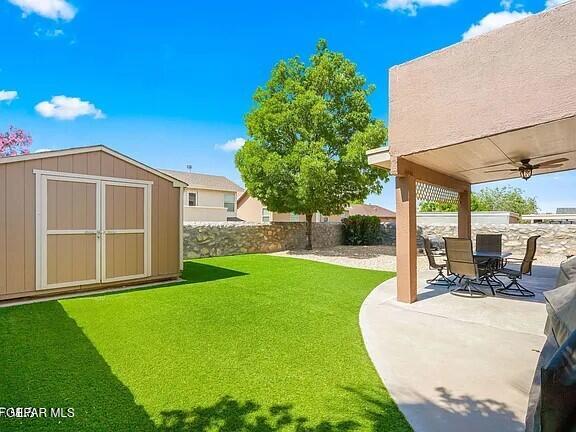 view of yard with a patio, ceiling fan, and a storage unit