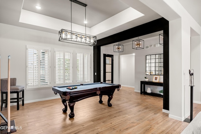 recreation room with a tray ceiling, light wood-type flooring, and baseboards