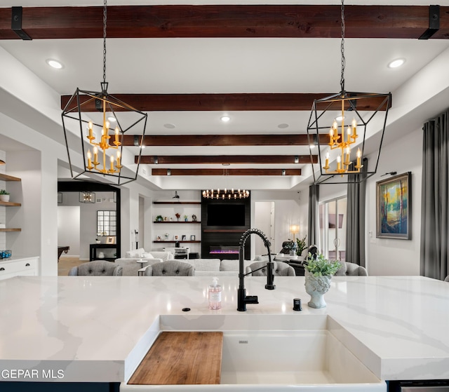 kitchen with pendant lighting, a center island with sink, an inviting chandelier, open floor plan, and a sink