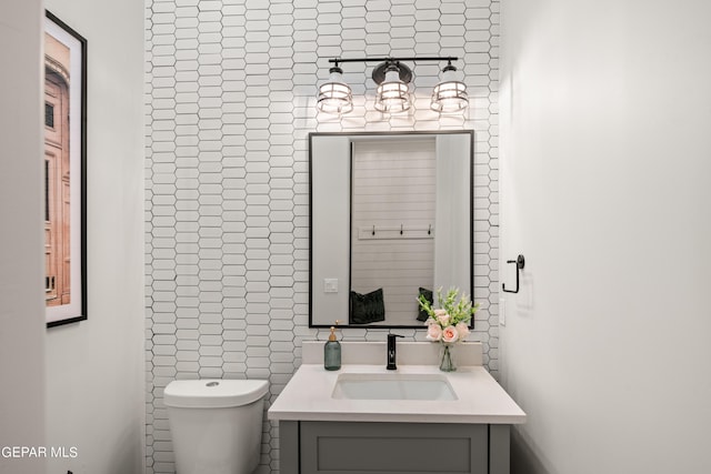 half bathroom with tile walls, vanity, and toilet