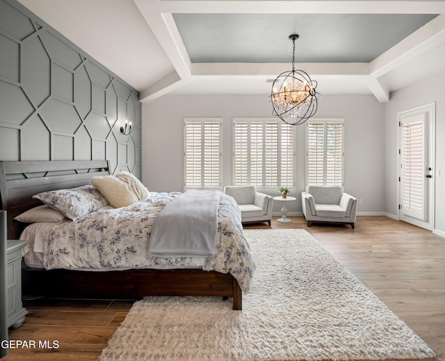 bedroom featuring an accent wall, light wood finished floors, multiple windows, and baseboards