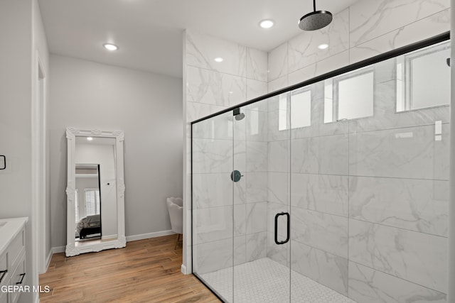 ensuite bathroom with a wealth of natural light, connected bathroom, a shower stall, and wood finished floors