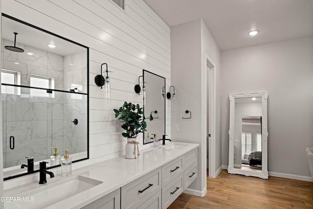 full bathroom featuring wood finished floors, plenty of natural light, a sink, and a marble finish shower