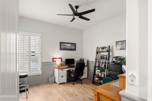 office space with plenty of natural light, wainscoting, a ceiling fan, and light wood-style floors