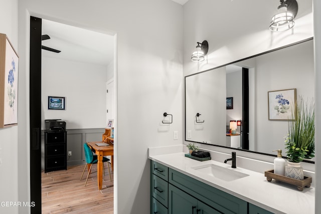 bathroom with wainscoting, a decorative wall, wood finished floors, and vanity