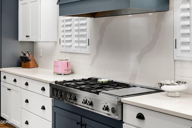 kitchen with white cabinets, stainless steel gas cooktop, light countertops, and ventilation hood