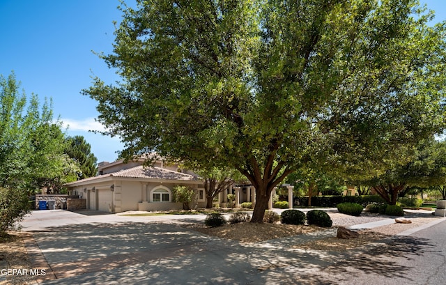 view of front of property with a garage, driveway, a tile roof, and stucco siding