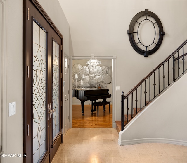 entryway featuring french doors, stairway, and an inviting chandelier