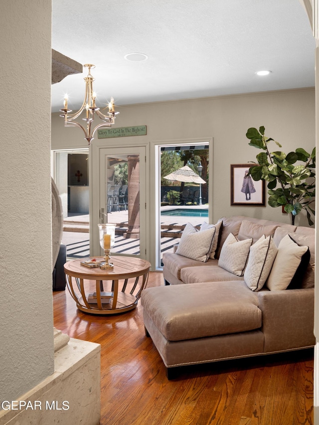 living room with a notable chandelier, wood finished floors, and a textured wall