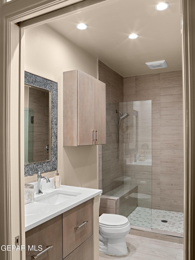 full bathroom featuring tiled shower, vanity, toilet, and recessed lighting