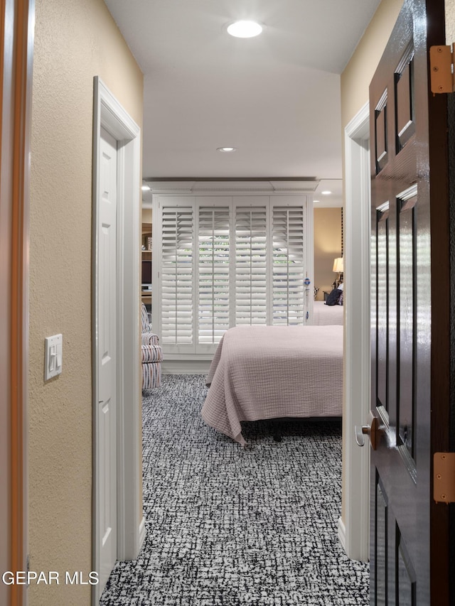 bedroom with a textured wall, dark colored carpet, and recessed lighting