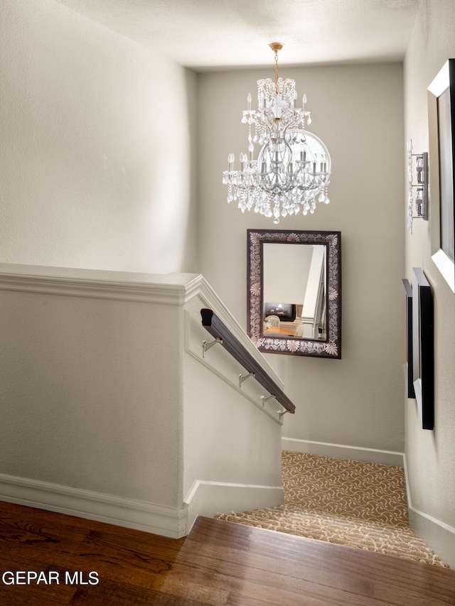 stairway featuring baseboards and a chandelier