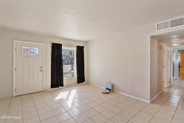 entryway with light tile patterned flooring and a textured ceiling