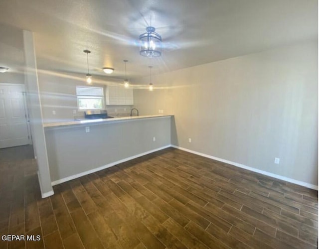 kitchen featuring hanging light fixtures, white cabinetry, dark hardwood / wood-style flooring, and kitchen peninsula