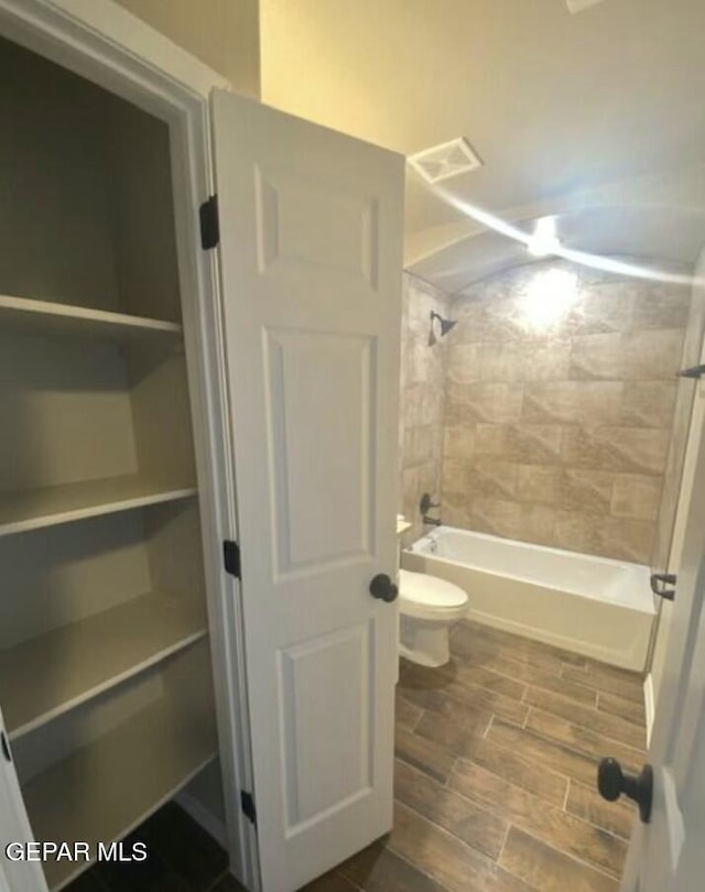 bathroom with toilet and tiled shower / bath combo