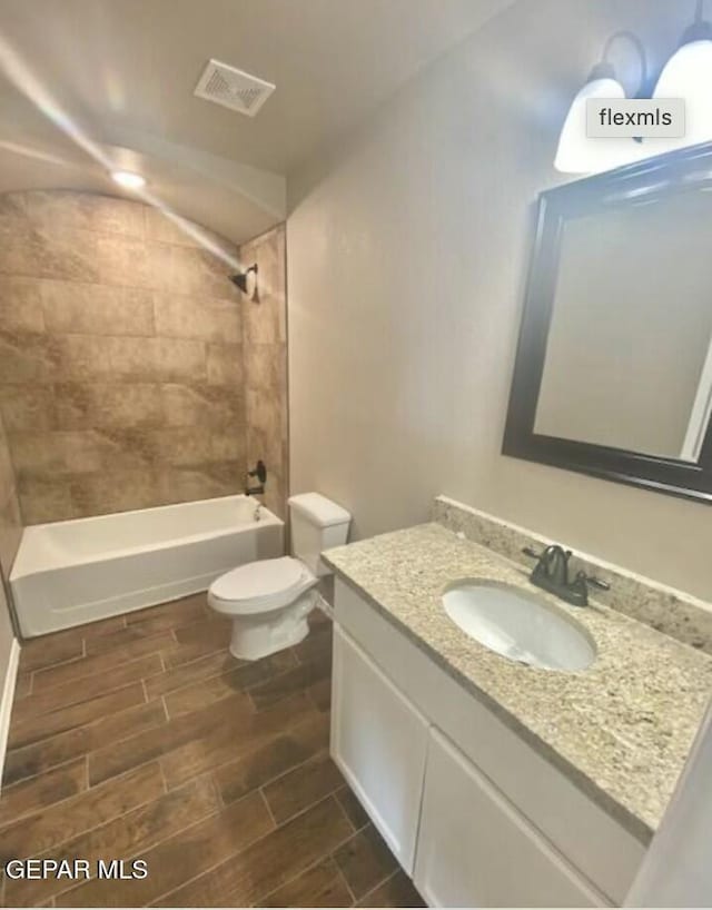 full bathroom featuring tiled shower / bath, vanity, and toilet