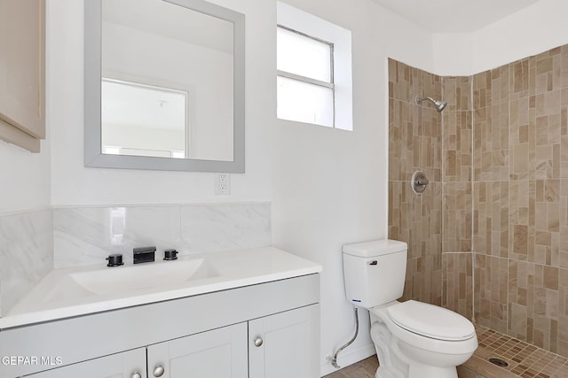 bathroom with vanity, toilet, and a tile shower