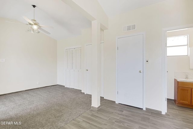 unfurnished bedroom with two closets, sink, ceiling fan, ensuite bath, and light hardwood / wood-style flooring