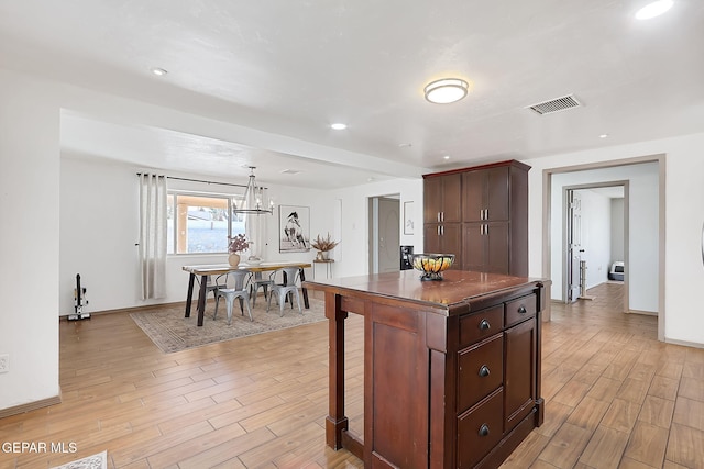 kitchen with a breakfast bar, dark brown cabinets, a notable chandelier, a kitchen island, and decorative light fixtures