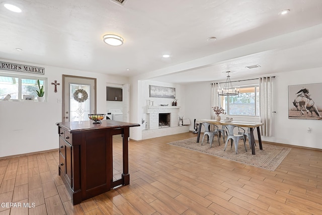 kitchen featuring washer / dryer, pendant lighting, a wealth of natural light, and a fireplace