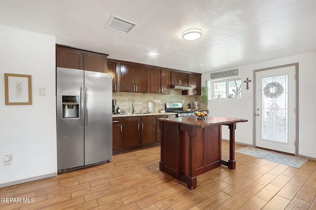 kitchen with sink, a center island, dark brown cabinets, appliances with stainless steel finishes, and backsplash