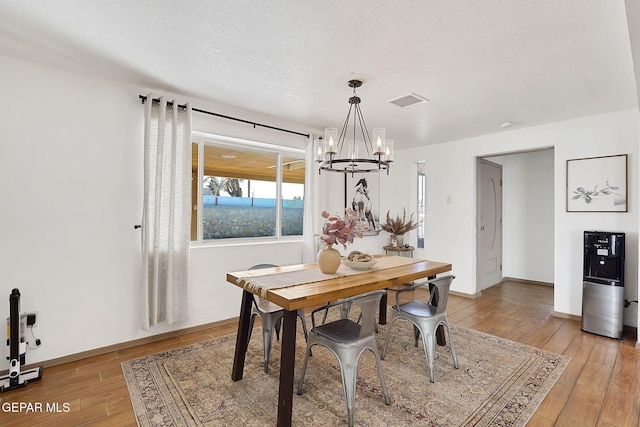 dining space featuring hardwood / wood-style flooring, a chandelier, and a textured ceiling