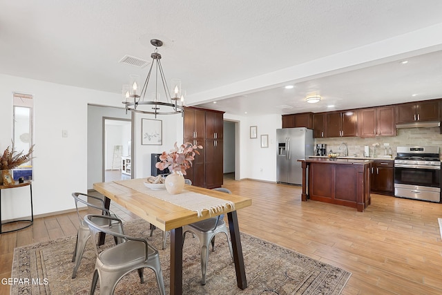 dining room with beam ceiling, sink, an inviting chandelier, and light wood-type flooring