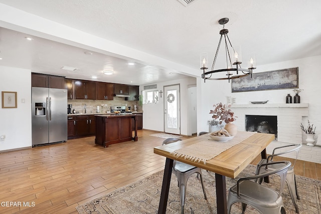 dining room with a chandelier, a fireplace, and light wood-type flooring