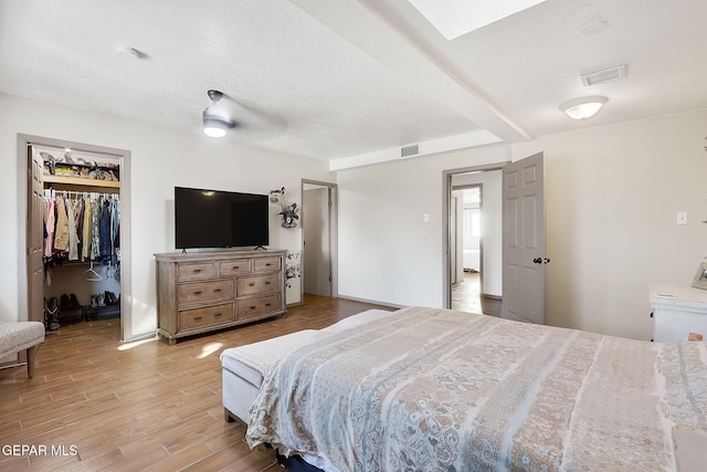 bedroom with a walk in closet, ceiling fan, and a closet