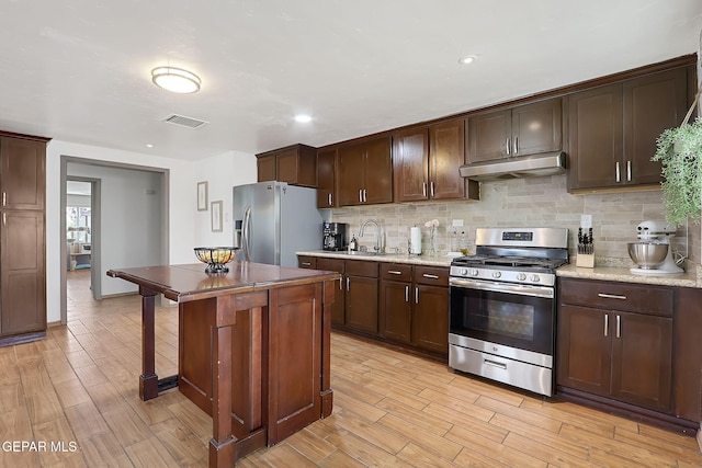 kitchen with sink, light hardwood / wood-style flooring, backsplash, stainless steel appliances, and dark brown cabinetry