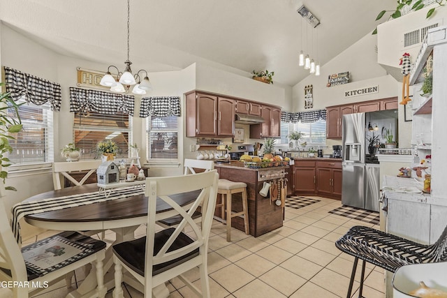 kitchen featuring high vaulted ceiling, hanging light fixtures, light tile patterned floors, a notable chandelier, and stainless steel appliances