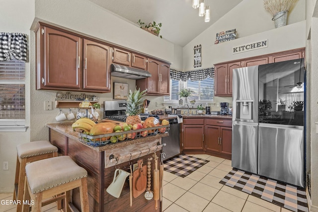 kitchen featuring light tile patterned flooring, lofted ceiling, sink, a kitchen breakfast bar, and stainless steel appliances