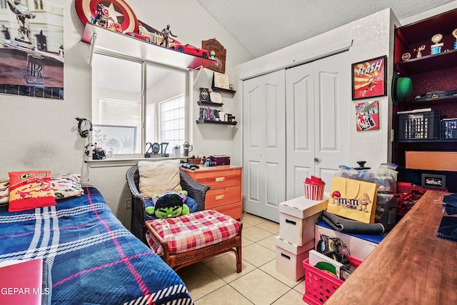 bedroom featuring light tile patterned floors, vaulted ceiling, a closet, and a textured ceiling