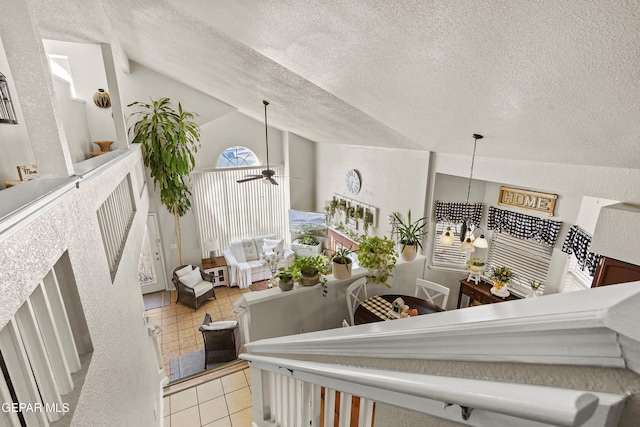 stairs with ceiling fan, lofted ceiling, tile patterned flooring, and a textured ceiling