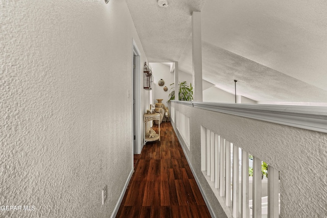 hall with dark hardwood / wood-style flooring, vaulted ceiling, and a textured ceiling