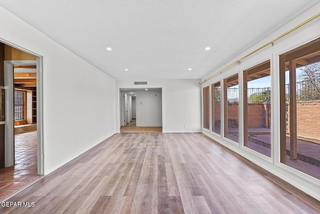 interior space featuring recessed lighting, visible vents, a textured ceiling, and wood finished floors