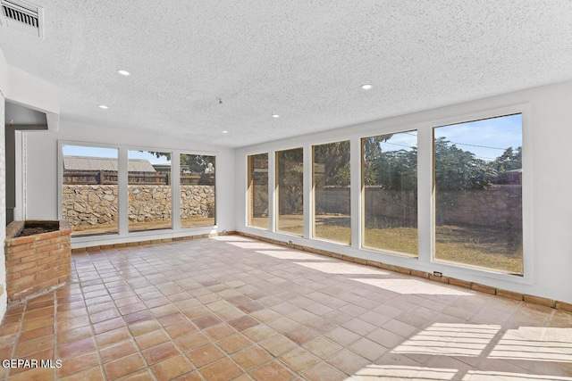 unfurnished sunroom with recessed lighting, visible vents, a textured ceiling, and baseboards