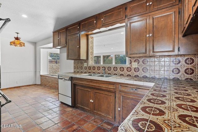 kitchen featuring tasteful backsplash, tile counters, wainscoting, dishwasher, and a sink