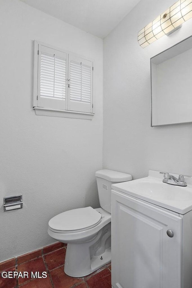 half bathroom with tile patterned flooring, toilet, and vanity