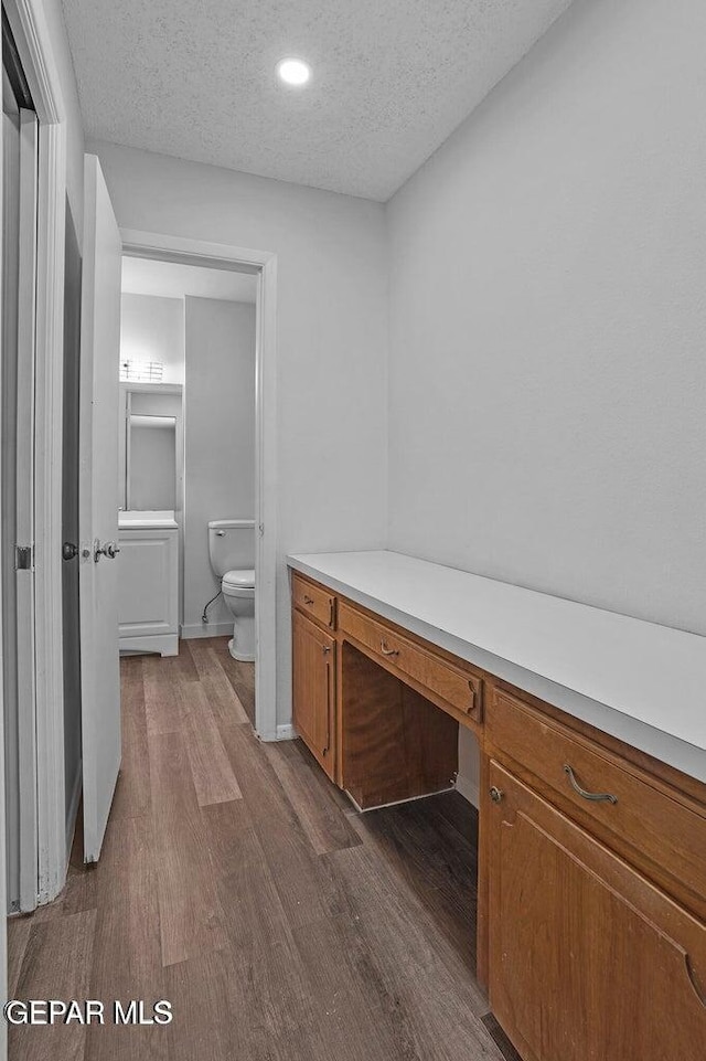 interior space featuring dark wood-style flooring, built in study area, baseboards, and a textured ceiling