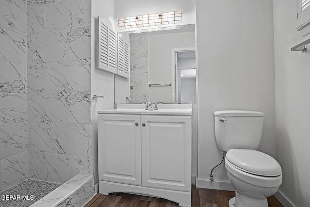 bathroom with vanity, a tile shower, toilet, and wood finished floors