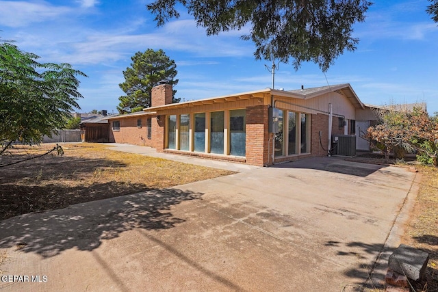 back of house with central AC unit, a patio area, fence, brick siding, and driveway