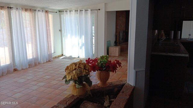 8808 Cosmos Ave, El Paso, TX 79925 - tiled dining room featuring a sink, a textured ceiling, and a fireplace