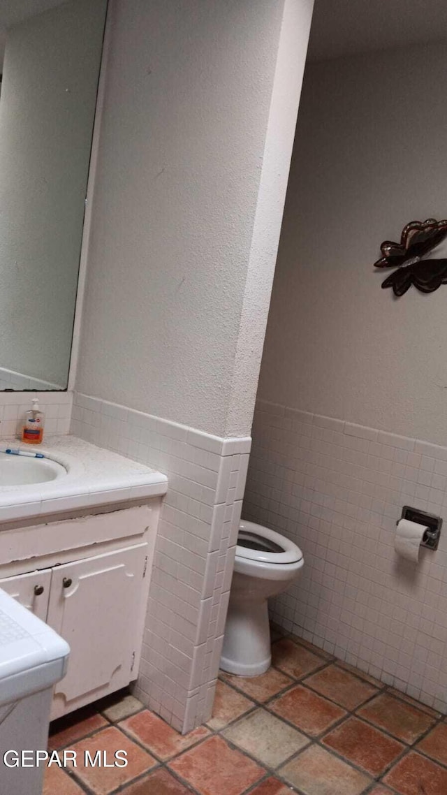 8808 Cosmos Ave, El Paso, TX 79925 - bathroom with tile walls, toilet, vanity, and wainscoting