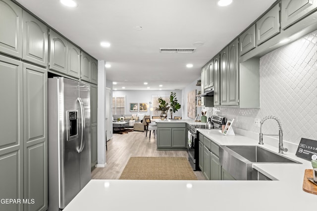 kitchen with appliances with stainless steel finishes, sink, gray cabinetry, backsplash, and light wood-type flooring